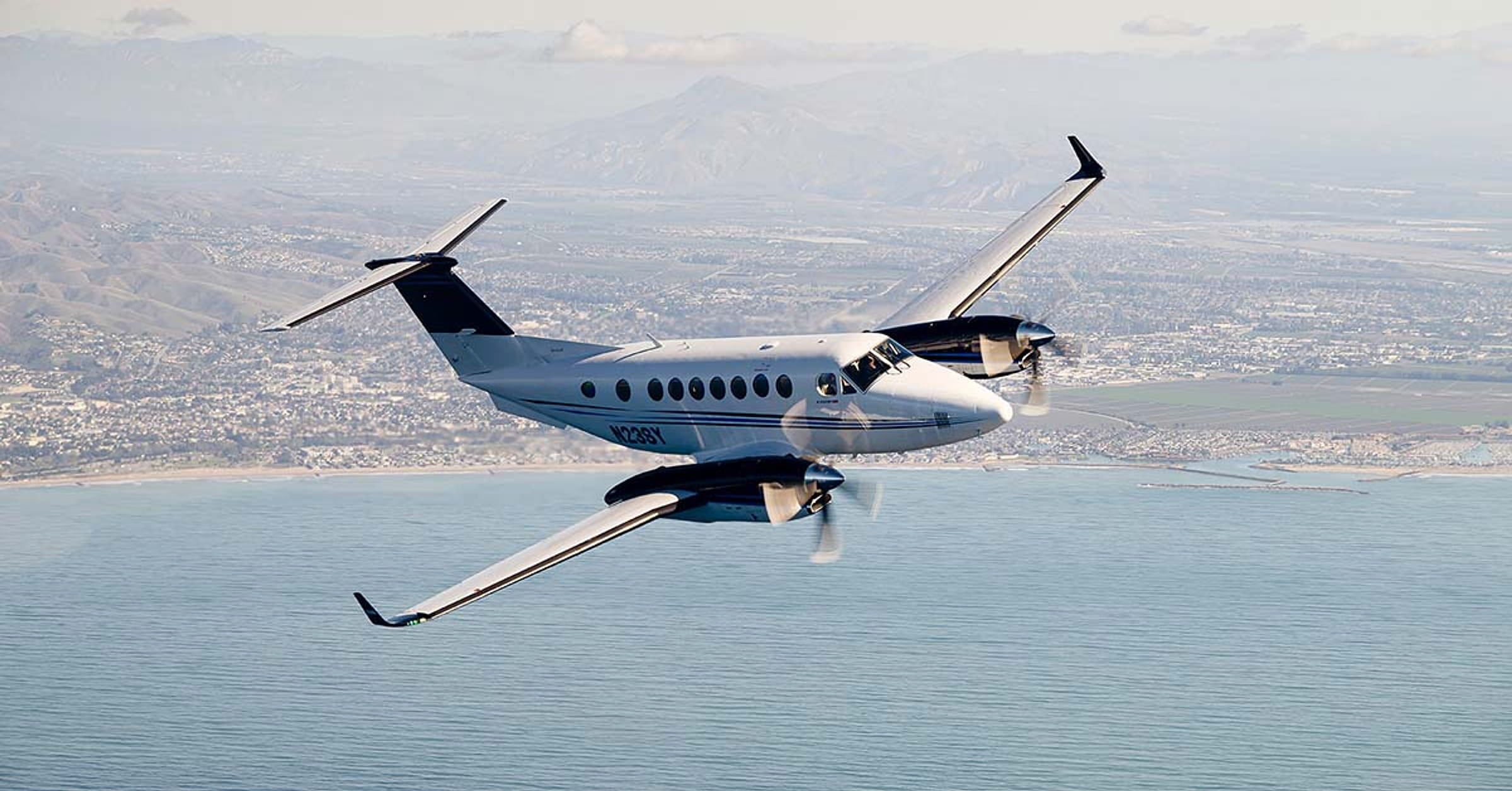 A Clipper Aviation King Air 350 in a banking turn above the Southern California coastline